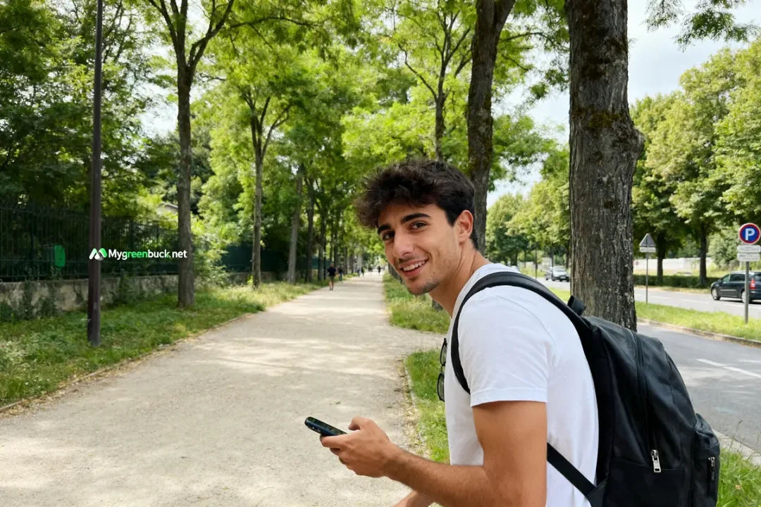 Jeune homme souriant avec sac à dos dans un parc Mygreenbucks net Jones visible
