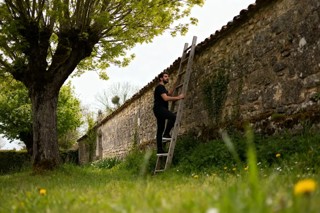 Homme montant une échelle en bois contre un mur de pierre blog L'Échelle de Jacob