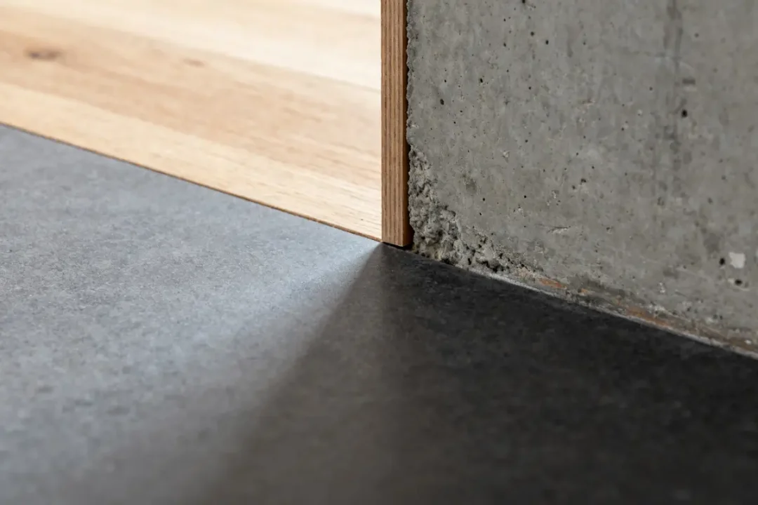 Sol gris anthracite se mélangeant avec parquet en bois et mur en béton apparent