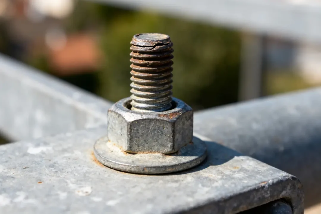 Boulon sur métal avec pas de vis foiré et rouille visible sur la surface